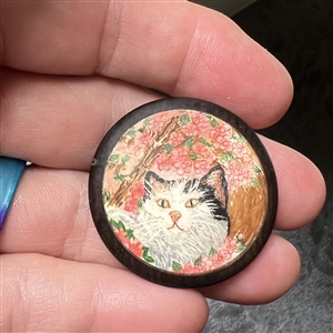 Hand painted natural material of a cat under cherry blossoms button.